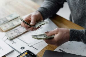 Close up of hands counting one dollar bills.