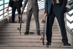 Men in business suits balancing skateboards on a stairway.