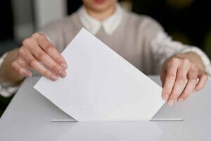 Woman putting a ballot into a ballot box.